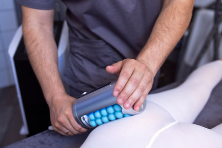 Faceless beautician using massager to remove fat from hips of anonymous customer in salon....