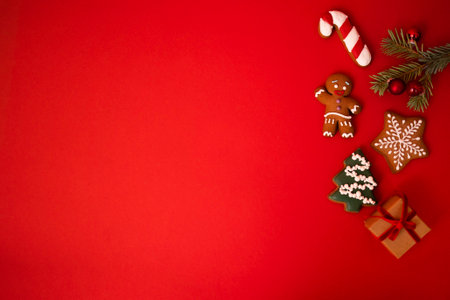 Cute red holiday background with cookies, sprig of fir tree with Christmas balls and a gift in craft...