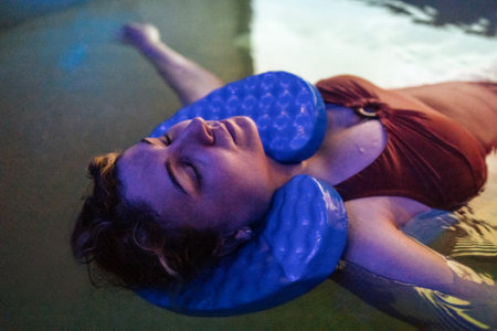 A young woman in a red swimsuit is swimming in the pool. An attractive plump girl enjoys a spa procedure in the salt room. A charming woman relaxes in salt water.の写真素材