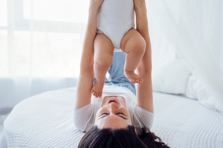 Young beautiful mother kisses her cute baby on cheek. White brunette touches her smiling child with...