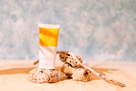 Mockup tubes with sunscreen on textured stones with a tree root. A podium for cosmetic products with a layout of an empty bottle on the sand. Sunlight and shade from a palm leaf.の写真素材