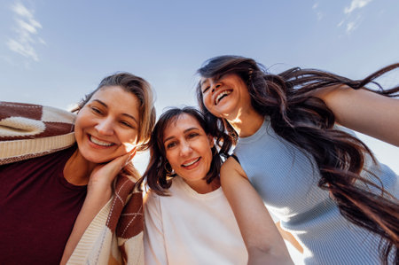 A group of young attractive multiethnic women take selfies and laugh outdoors. Smiling female friends of different races have fun and take pictures in nature. Bottom view.の写真素材