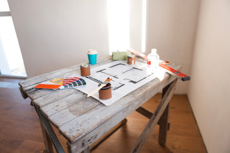 Plan of renovation of house on old wooden table. Top view. Sheet of paper with cans of paint and...