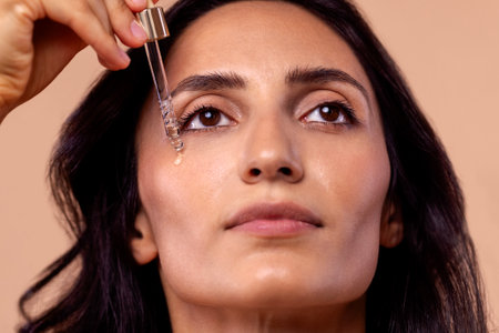 Close-up of charming woman holding pipette with regenerating serum with hyaluronic acid. Attractive girl with beautiful healthy skin and moisturizing anti-aging facial essence.の写真素材