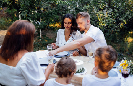Happy family is having lunch at a table outside. Mom, dad, two sons are on the open veranda of the house or an open cafe. They are celebrating a birthday. Copy space.の写真素材