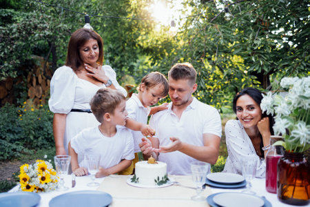 Happy family is having lunch at a table outside. Mom, dad, two sons are on the open veranda of the house or an open cafe. They are celebrating a birthday. Copy spaceの写真素材