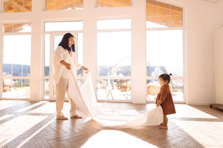 A young Asian woman is playing with her cute kids at home. Happy Korean family. A laughing mom is having fun with her little son and daughter in the living room.の写真素材