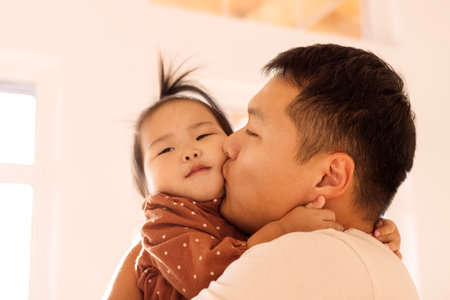 A close-up portrait of an Asian little girl and her dad. A young Korean father is holding his cute...