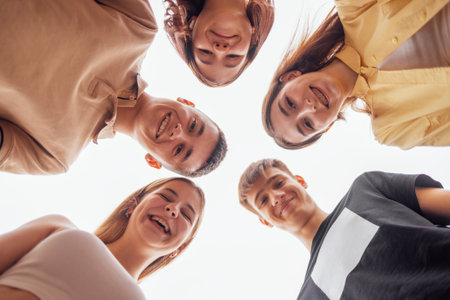 Funny smiling teenagers standing and looking down at camera. Group of cheerful friends in casual...