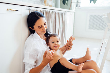 A young attractive woman holds her smiling son in her arms. A funny boy is playing with his mom. A...
