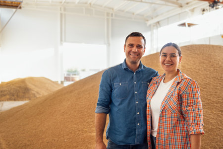 A young married couple are smiling in a grain barn. A charming woman and an attractive man in casual...