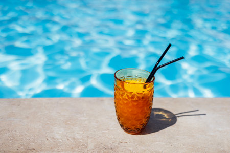 Delicious chilled fresh orange juice with straws on the side of the pool. Tasty citrus cocktail on...