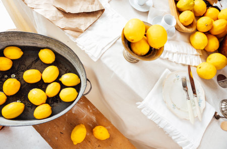 Juicy fresh lemons and daisies in water in a vintage metal basin. Top view. Wooden retro bench with...
