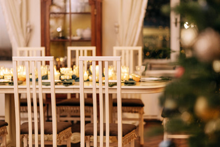 A dining table covered with candles and Christmas decor. Empty cutlery. Waiting for the guests. A...