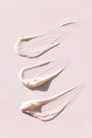 Close-up of the texture of pink cream on a light background. Moisturizing serum is smeared on the...