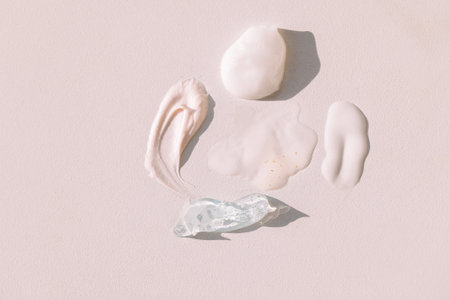 A collection of different lotions and creams are spread out on a table. Texture of gel and serum on a light background. A cosmetic strokes are a transparent essence with colloidal gold and bubblesの写真素材
