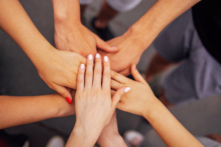 Female and male hands are placed on top of each other. The arms of women and men are folded as a symbol of support and command. A friendly group motionの写真素材