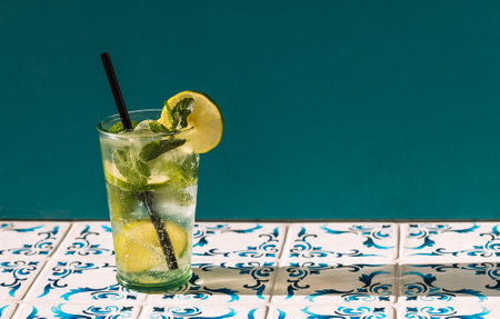 Close-up of a glass of delicious mojito with lime and fresh mint. Tasty lemonade with ice cubes on a...