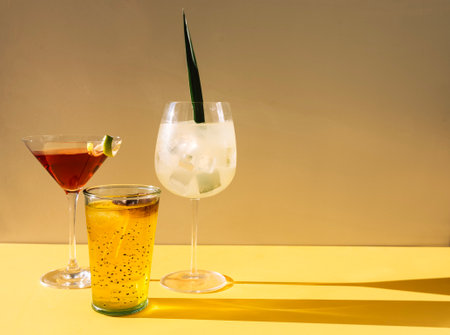 Close-up of three different multicolored drinks. Glasses with cocktails on a beige background. Fresh fruit drinks with ice. Sunlight. Minimalism. Copy spaceの写真素材