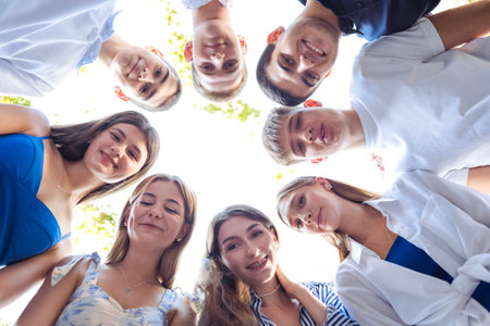 A group of young people in casual clothes are smiling and posing. Bottom view. Laughing boys and...