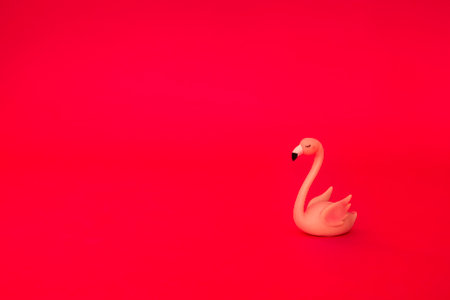 A pink flamingo figurine on a pink background. Cute statuette of an exotic sleeping bird on an...