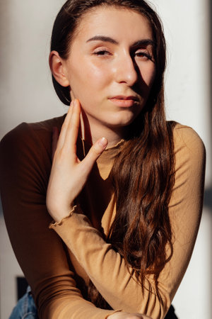 Close-up portrait of a young girl in bright sunlight. Cute teen in casual clothes poses indoorsの写真素材