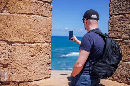 Happy tourist man visiting Essaouira, Marrakech, Morocco. Taking mobile photo picture on summer vacation. Holidays and tourism conceptの写真素材