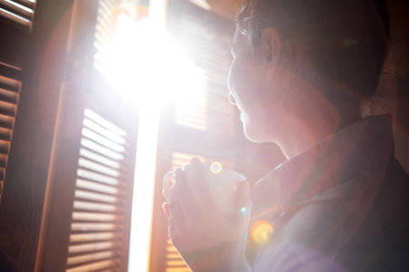 Close-up of a young woman in casual clothes holding a cup of coffee and smiling. A girl is drinking tea and laughing in the living room. Lunch break for a female freelancer at her home officeの写真素材