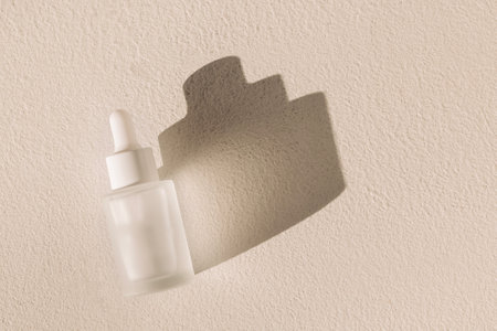 A mock-up of a bottle of moisturizing serum with a pipette on a textured white background. Frosted glass flask with an anti-aging essence dropper. Bright light and shadow. Minimalismの写真素材
