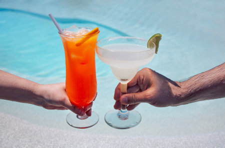 Male and female hands hold out glasses with tasty cocktails for a toast. A woman and a man celebrate...
