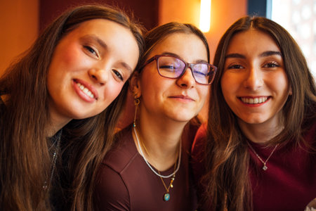 Close-up portraits of three laughing young girls in casual clothes indoors. Happy teenagers posing...
