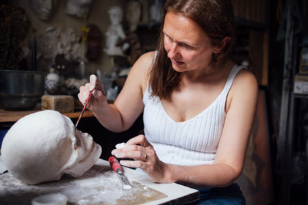 Artist is painting a sculpted head in a creative studio, with various artistic tools and materials...