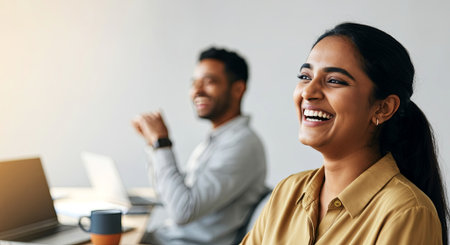 South Asian woman smiles brightly in a professional environment, interacting with a colleague, emphasizing collaboration and a vibrant office atmosphere, AI generatedの素材