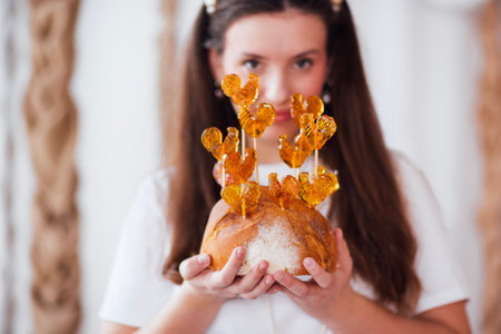 Female baker presents a unique bread loaf adorned with golden heart decorations, emphasizing...