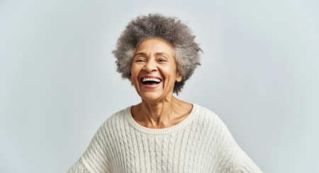 Happy African American woman with gray hair, dressed in a soft white sweater, smiles joyfully against a light pastel backdrop, conveying a sense of warmth and positivity, AI generatedの素材