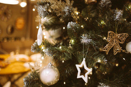 Festive Christmas tree decorated with white and gold ornaments, twinkling lights, and a warm ambiance, enhancing the cozy living room for holiday gatheringsの写真素材
