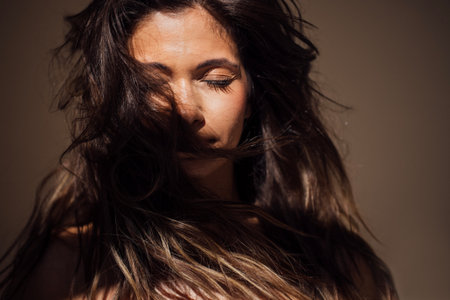 Female figure with long hair, eyes closed, stands against a soft backdrop, embodying tranquility and grace, reflecting a moment of peaceful contemplationの写真素材