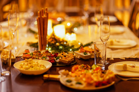 Close-up of delicious snacks on a festive table. Candles and Christmas decorations. Plates and glasses. Tasty dishes for a celebratory lunch. Copy spaceの写真素材