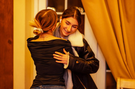 Two girls hug on the threshold of the house. Friends laugh and rejoice togetherの写真素材