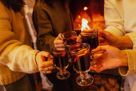 Close-up of the women saying a toast and clinking glasses with mulled wine. Cups of spicy hot Christmas drink at a house party. New Year Eve. Meeting family and friendsの写真素材