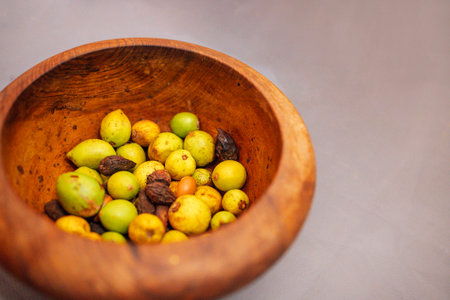 Assorted fresh argan nut in a wooden bowl, highlighting vibrant colors and textures, placed on a neutral background, creating a natural and organic atmosphereの写真素材
