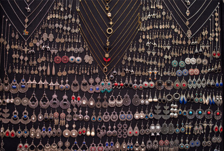 Detailed arrangement of silver jewelry pieces on a dark backdrop, highlighting diverse earrings and necklaces, emphasizing elegance and artistic craftsmanshipの写真素材