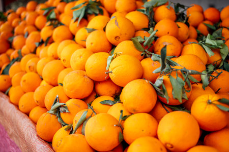 Fresh oranges with green leaves are beautifully arranged in a vibrant pile at a market, highlighting the natural beauty and abundance of citrus fruitsの写真素材