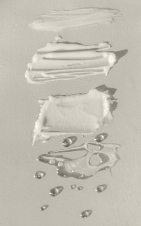 Different texture of gel and cream on a yellow background. Transparent and white serum with drops....