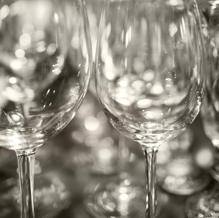Extreme closeup of empty champagne glasses in a row. Wine goblet at wedding reception, alcohol bar, catering in restaurant. Blurred beautiful background.の写真素材