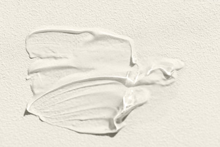 The texture of the cream on a light background. Translucent serum is smeared on the backdrop. The...