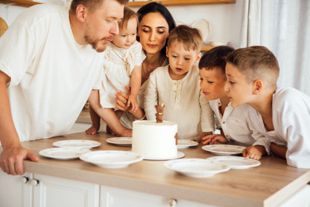 Family members are gathered around a birthday cake in a cozy kitchen, sharing smiles and excitement, creating joyful moments filled with love and togethernessの写真素材