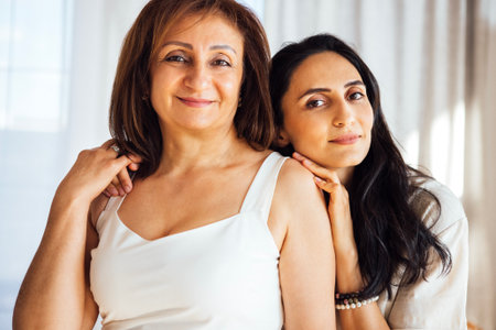 Older woman and her daughter are standing together in a well-lit room, demonstrating affection and familial connection in a cozy environmentの写真素材