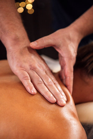 Male therapist is performing a calming back massage in a tranquil spa setting, highlighting the...