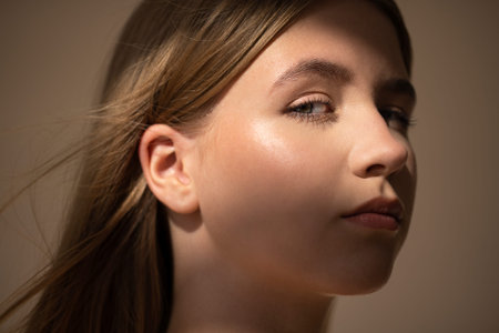 Female with long hair gazes thoughtfully, illuminated by soft light, creating a serene ambiance that...